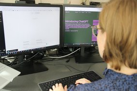 Frau sitzt vor PC mit ChatGPT geöffnet.