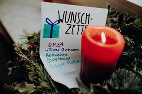 Wunschzettel neben einer roten Kerze