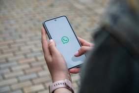 Hand hält ein Smartphone mit WhatsApp Startbildschirm