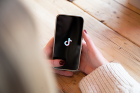Hand hält Smartphone mit TikTok-Logo auf dem Display